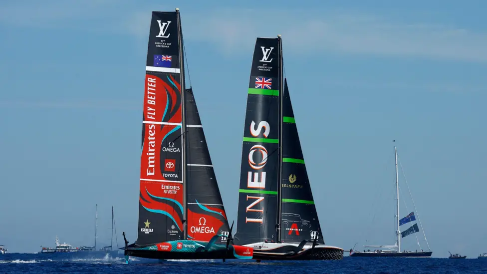 October 19, 2024: Team New Zealand Clinches Third Consecutive America's Cup VictoryA Historic Achievement This victory solidifies Team New Zealand's status as the most dominant force in modern America's Cup racing. Their "three-peat" - consecutive wins in 2017, 2021, and now 2024 - is an unprecedented feat that showcases their unparalleled mastery of the world's oldest international sporting trophy.Skipper Peter Burling, visibly moved after the final race, stated, "It's an incredible feeling. It's been a tough battle all week, but an amazing final score, and I'm really proud of how the team kept fighting today". Technical and Tactical Brilliance Team New Zealand's success is built on a perfect blend of technological innovation and tactical excellence. Their AC75 yacht, named Taihoro, proved to be an engineering marvel, capable of exceptional performance across all conditions.The Kiwi crew demonstrated impressive skill, particularly through the helming duo of Peter Burling and Nathan Outteridge. Their seamless communication and ability to read the changing conditions were crucial throughout the competition. INEOS Britannia: A Valiant but Insufficient Challenge Despite notable improvements in their performance as the competition progressed, the British INEOS Britannia team couldn't match the consistency and speed of the New Zealanders. Skipper Ben Ainslie paid tribute to their opponents, describing them as "the best team in America's Cup history". The Future of the Cup This victory raises questions about the future of the competition. As the Defender, Team New Zealand will have the responsibility of defining the format and location of the next edition. Speculation is rife about a possible return of the event to New Zealand, although financial considerations may influence this decision. Conclusion Team New Zealand's victory in Barcelona confirms their legendary status in the sailing world. Their ability to innovate, adapt, and perform at the highest level makes them worthy holders of the Auld Mug. As the sailing world celebrates this historic achievement, all eyes are already turning to the next edition of the America's Cup, where Team New Zealand will undoubtedly aim to extend their remarkable winning streak.